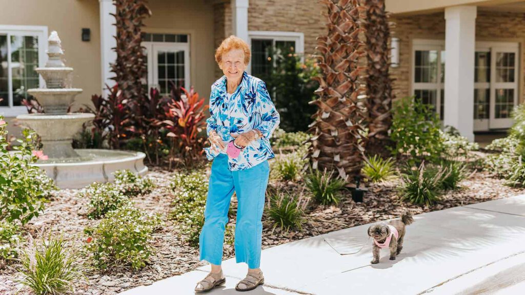 Senior woman walking small dog in courtyard